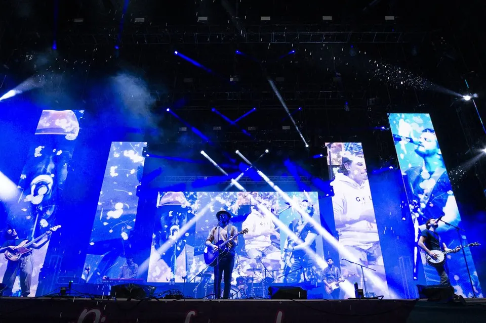 Morat en un gran escenario con pantallas que muestran a los músicos y focos azules cruzando el aire