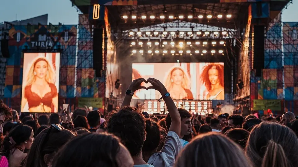 Público frente al escenario Turia de BIGSOUND Valencia al atardecer, con una persona formando un corazón con las manos y pantallas gigantes encendidas a los lados