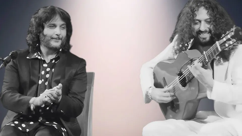 El cantaor Antonio Reyes, sentado y dando palmas con una camisa de lunares, y el guitarrista Joni Jiménez, vestido de blanco y sonriendo mientras toca la guitarra, en un montaje en blanco y negro
