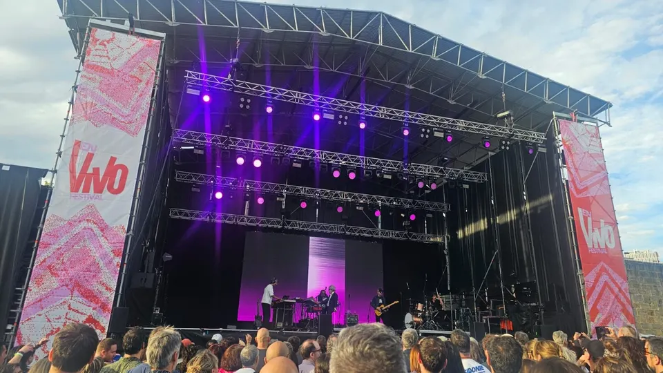 Escenario cubierto de la Ciudadela de Pamplona durante el festival En Vivo de 2026: estructura metálica con focos morados, estandartes del festival a los lados y el público en primer plano