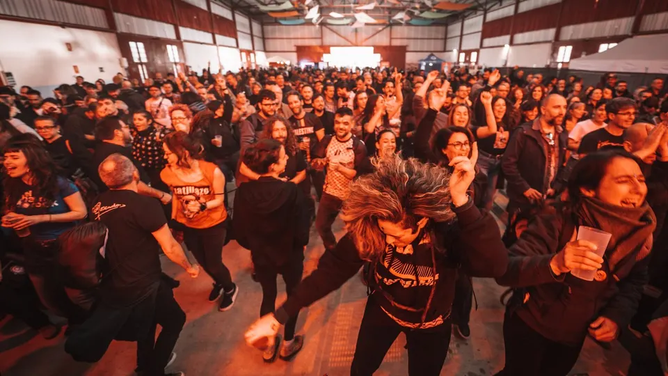 Público bailando y saltando dentro del Pabellón de Usos Múltiples de Huétor Tájar durante una edición anterior de +Espárrago Music and Sound Festival, con la nave llena hasta el fondo