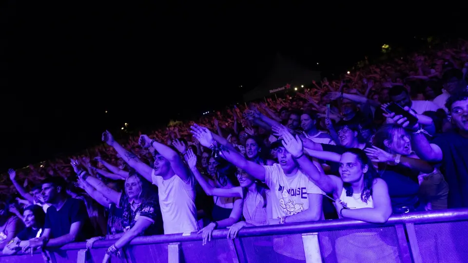 Público de Play4Life con los brazos en alto junto a la valla del escenario, de noche y bajo luces violetas, en una edición anterior del festival