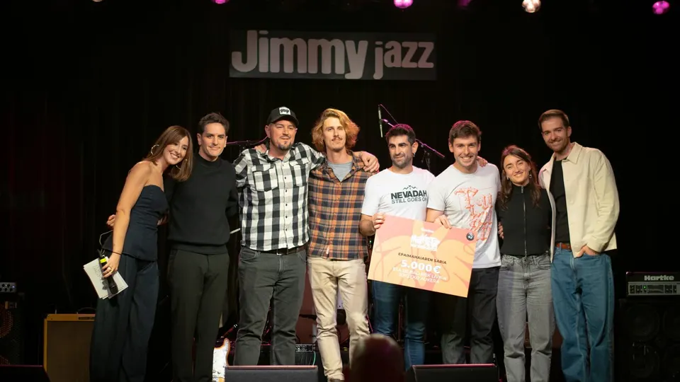 Ocho personas posan en el escenario del Jimmy Jazz de Vitoria-Gasteiz en la final del Maketa Lehiaketa 2025, con el cheque de 5.000 euros del premio del jurado y una actuación en el Bilbao BBK Live