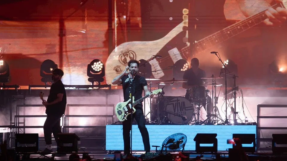 Viva Suecia en el escenario de Brisa Festival 2025: el cantante toca una guitarra clara frente al micrófono, con el bajista a la izquierda y la batería con el nombre del grupo detrás, bajo luces cálidas