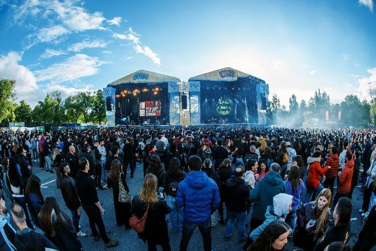 Público ante los dos escenarios de Bat Batean en Mendizabala durante la primera edición del festival, en 2026, en una tarde soleada con humo sobre el escenario