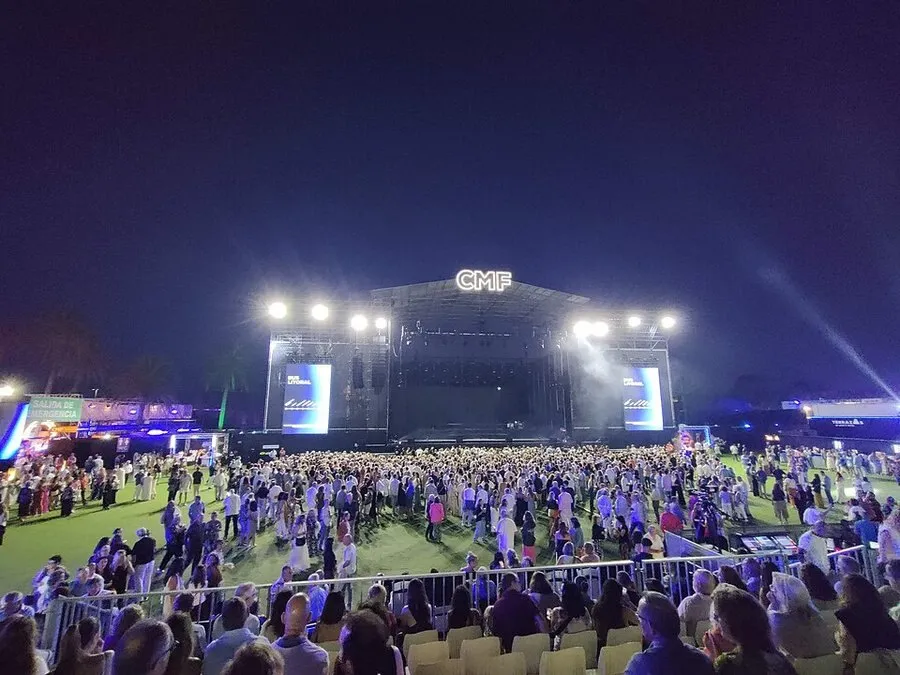 El escenario del Concert Music Festival, con el rótulo CMF iluminado sobre la estructura y el público reunido en la explanada de césped de Sancti Petri al caer la noche