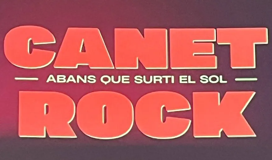 Rótulo de Canet Rock con el lema «Abans que surti el sol»: letras grandes de color coral sobre fondo granate y la frase en blanco entre las palabras Canet y Rock