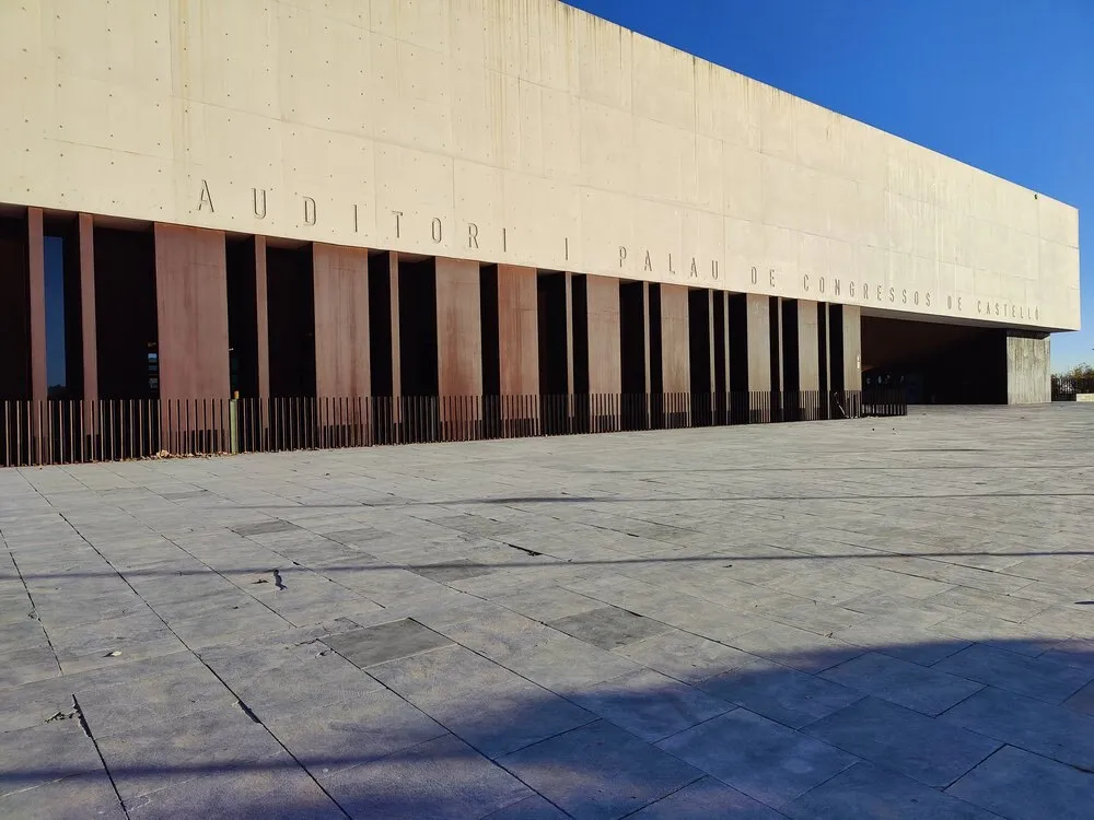 Fachada del Auditori i Palau de Congressos de Castelló, un edificio alargado de hormigón claro con columnas verticales, ante una gran explanada