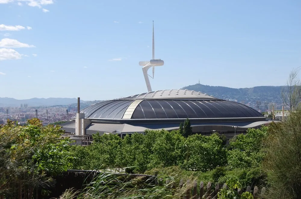 Vista exterior del Palau Sant Jordi en Montjuïc, con su cubierta metálica y la torre de comunicaciones de Calatrava al fondo