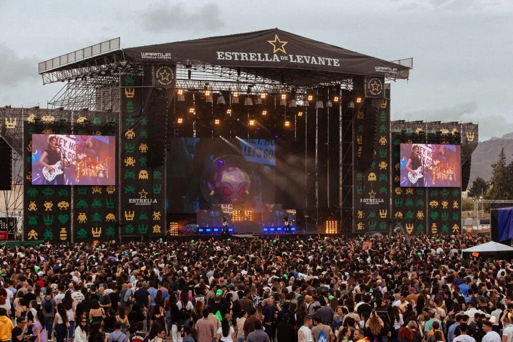 Escenario principal de WARM UP en La Fica, con el rótulo de Estrella de Levante en lo alto, pantallas a ambos lados y el público llenando la explanada