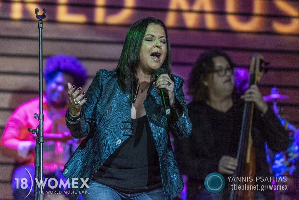 Olga Cerpa canta con los ojos cerrados y el micrófono en la mano, con músicos de Mestisay detrás, durante un showcase de WOMEX 2018 en Las Palmas de Gran Canaria