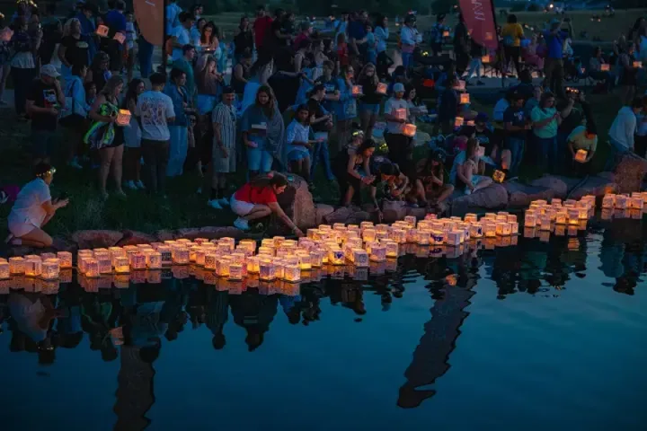 Participantes colocando linternas iluminadas sobre el agua