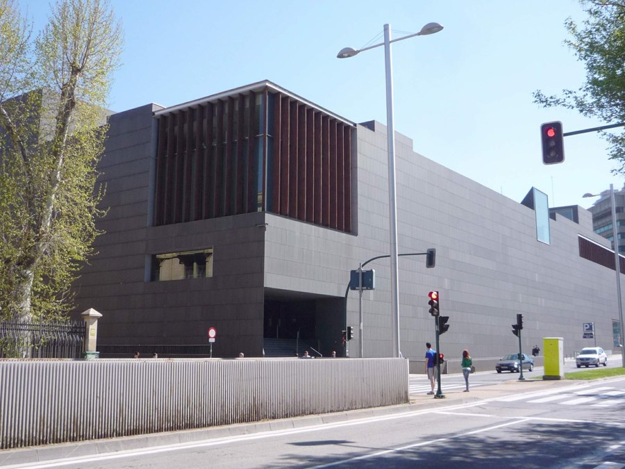 Exterior del auditorio Baluarte de Pamplona, un edificio de piedra oscura junto a una avenida arbolada