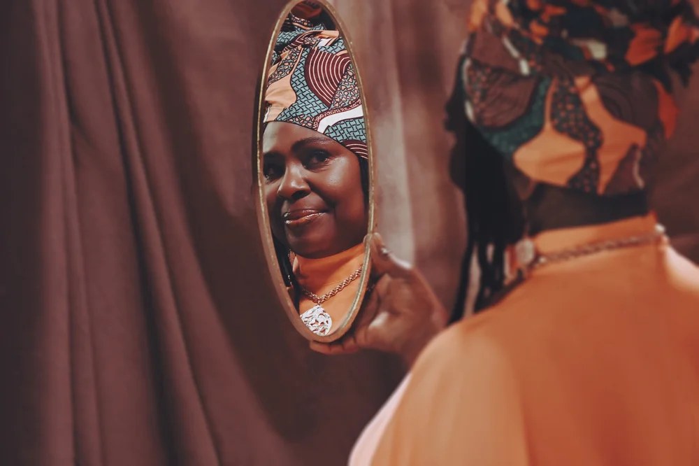 Ruthie Foster se mira en un espejo ovalado, con un pañuelo estampado en la cabeza, en una imagen promocional