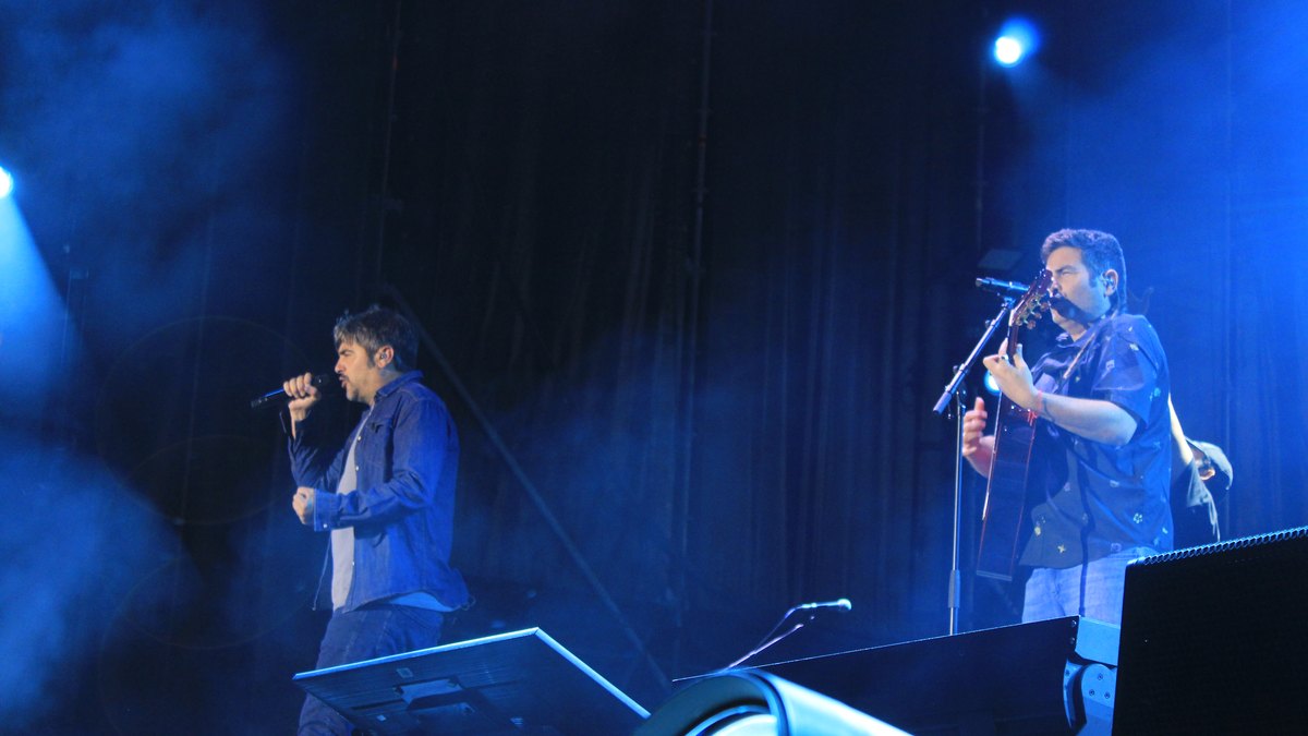 David y José Muñoz, de Estopa, cantando en el escenario iluminado de azul durante la gira de su 25 aniversario