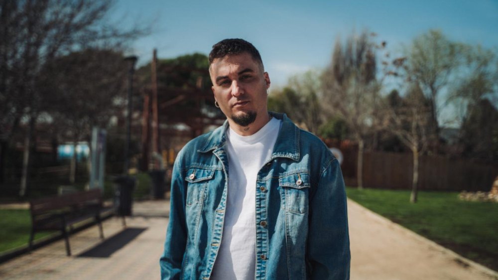 Ambkor, con chaqueta vaquera y camiseta blanca, en un parque, en la imagen promocional del Madrid Urban Fest 2026