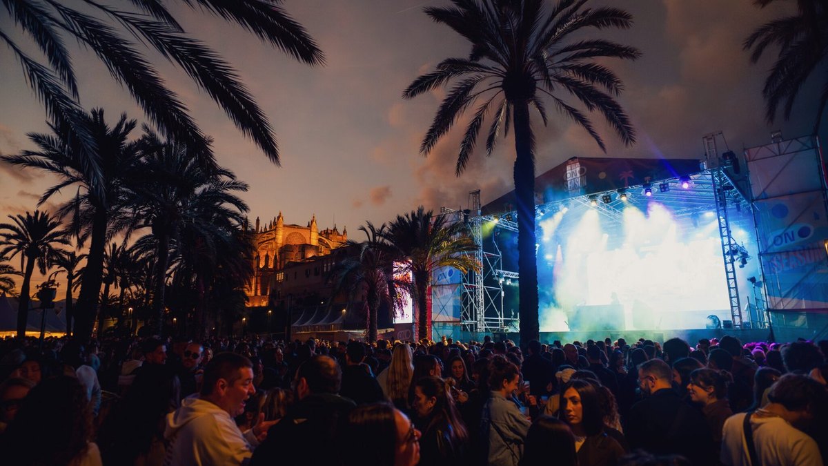 Público frente al escenario iluminado del Mallorca On Season Fest entre palmeras, durante la edición de marzo en el Parc de la Mar de Palma